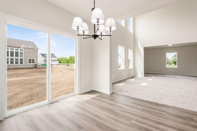 7014 Aster Way, Plain City, OH 43064 - unfurnished dining area with a chandelier, wood finished floors, baseboards, and a towering ceiling