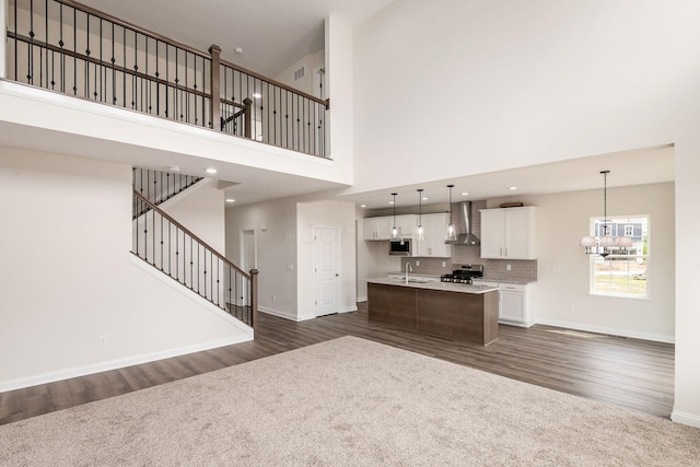 7014 Aster Way, Plain City, OH 43064 - kitchen featuring wall chimney exhaust hood, stainless steel appliances, a towering ceiling, dark wood-style flooring, and a sink