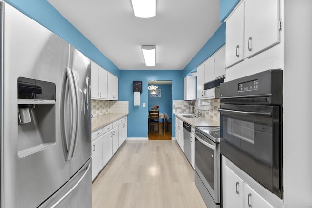 5280 Elmhurst Ave, Columbus, OH 43231 - kitchen with appliances with stainless steel finishes, a sink, light wood-style floors, backsplash, and white cabinetry