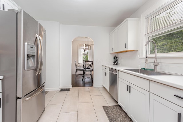 12 E Vine St, Jackson, OH 45640 - kitchen with stainless steel appliances, a sink, arched walkways, light countertops, and light tile patterned flooring