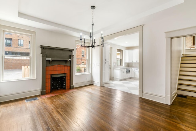 37 W 2nd Ave, Columbus, OH 43201 - unfurnished living room with a chandelier, stairway, light wood-style floors, a tile fireplace, and baseboards