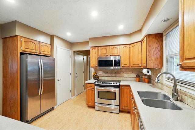 2517 Slateshire Dr, Dublin, OH 43016 - kitchen with appliances with stainless steel finishes, a sink, light wood finished floors, tasteful backsplash, and light countertops