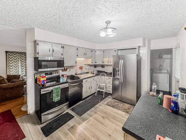 435 Alison Ct, Lancaster, OH 43130 - kitchen featuring appliances with stainless steel finishes, washer / dryer, light wood finished floors, dark countertops, and a sink