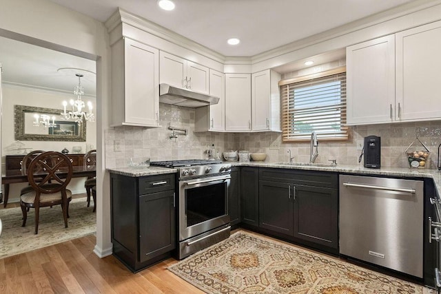 4606 Gershwin Ct, Grove City, OH 43123 - kitchen featuring appliances with stainless steel finishes, a sink, under cabinet range hood, white cabinets, and crown molding