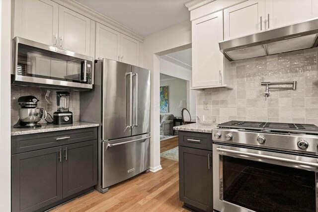 4606 Gershwin Ct, Grove City, OH 43123 - kitchen featuring appliances with stainless steel finishes, under cabinet range hood, tasteful backsplash, and light wood finished floors