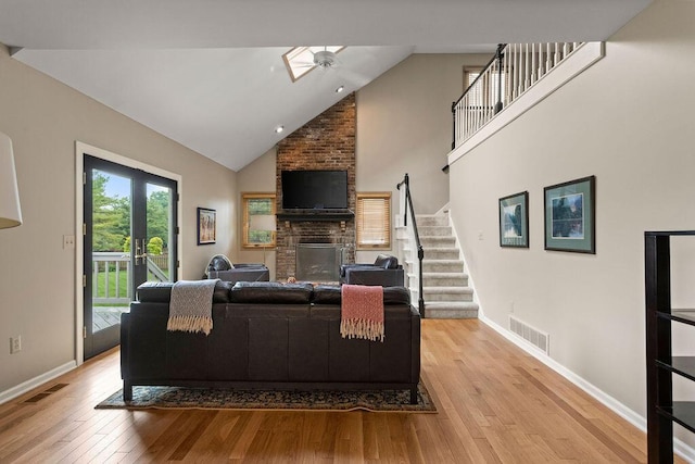 4606 Gershwin Ct, Grove City, OH 43123 - living area featuring light wood-style flooring, a brick fireplace, high vaulted ceiling, stairway, and baseboards