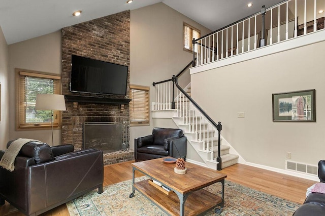 4606 Gershwin Ct, Grove City, OH 43123 - living area featuring stairs, a brick fireplace, wood finished floors, high vaulted ceiling, and baseboards