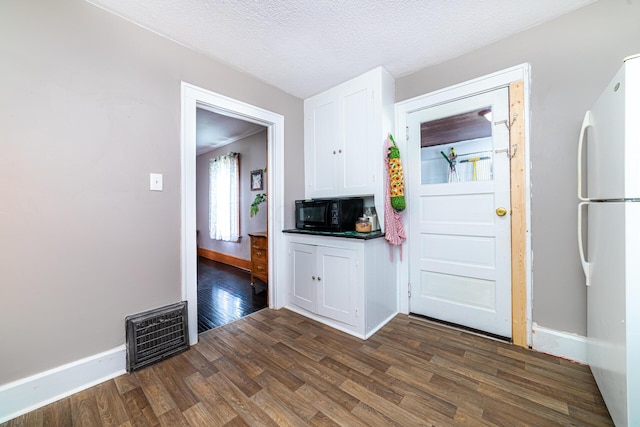 236 Ruth Ave, Mansfield, OH 44907 - kitchen with freestanding refrigerator, black microwave, white cabinets, dark wood-style floors, and baseboards
