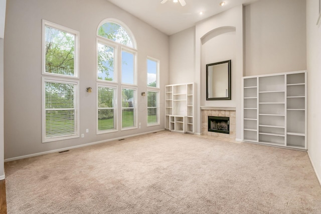 7985 Eric Ct, Lewis Center, OH 43035 - unfurnished living room featuring a high ceiling, carpet flooring, a tiled fireplace, a ceiling fan, and baseboards