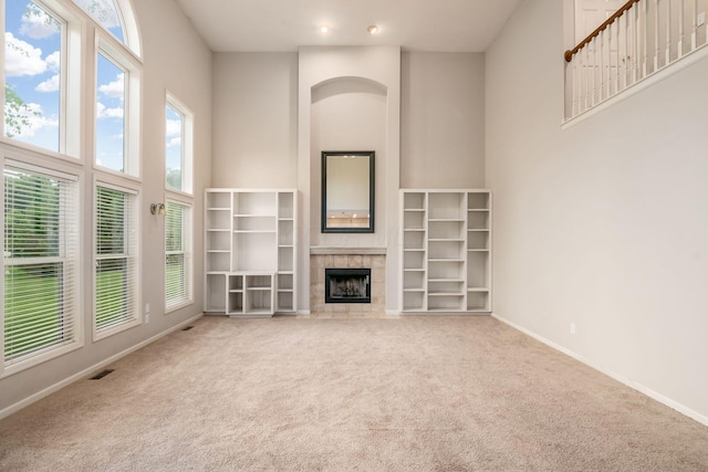 7985 Eric Ct, Lewis Center, OH 43035 - unfurnished living room with a towering ceiling, carpet, a tile fireplace, and baseboards