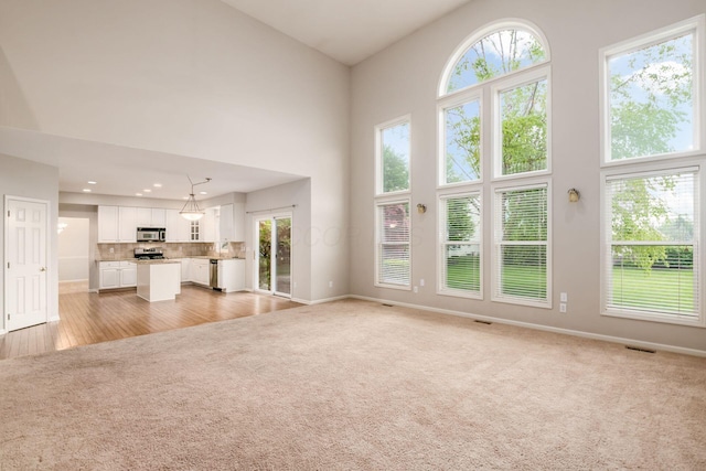 7985 Eric Ct, Lewis Center, OH 43035 - unfurnished living room featuring light carpet, a high ceiling, and baseboards