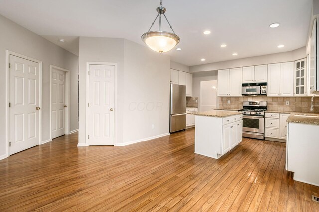 7985 Eric Ct, Lewis Center, OH 43035 - kitchen featuring appliances with stainless steel finishes, a sink, a kitchen island, tasteful backsplash, and light wood finished floors