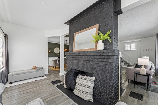 211 Guernsey Ave, Columbus, OH 43204 - living room featuring wood finished floors, stairway, a brick fireplace, and baseboards