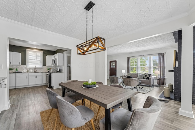 211 Guernsey Ave, Columbus, OH 43204 - dining space featuring an ornate ceiling, healthy amount of natural light, light wood-type flooring, a chandelier, and ornamental molding
