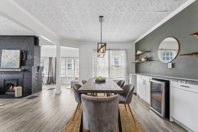 211 Guernsey Ave, Columbus, OH 43204 - dining space featuring wine cooler, an ornate ceiling, light wood-style flooring, a chandelier, and crown molding