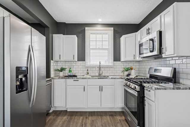 211 Guernsey Ave, Columbus, OH 43204 - kitchen with stainless steel appliances, a sink, a textured ceiling, light stone counters, and white cabinetry
