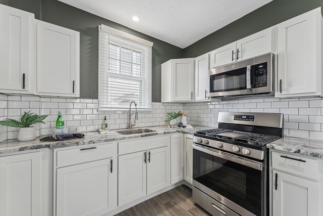 211 Guernsey Ave, Columbus, OH 43204 - kitchen featuring appliances with stainless steel finishes, a sink, a textured ceiling, white cabinetry, and wood finished floors