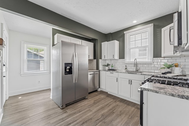 211 Guernsey Ave, Columbus, OH 43204 - kitchen with appliances with stainless steel finishes, a sink, light wood finished floors, white cabinets, and a textured ceiling