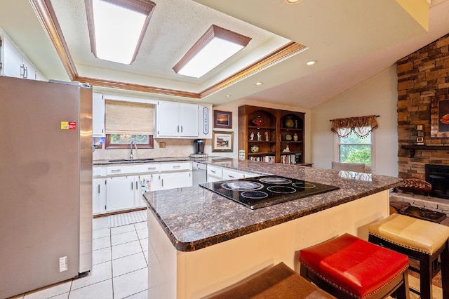 1027 Peggys Cv, Reynoldsburg, OH 43068 - kitchen featuring freestanding refrigerator, black electric stovetop, a sink, white cabinetry, and a peninsula