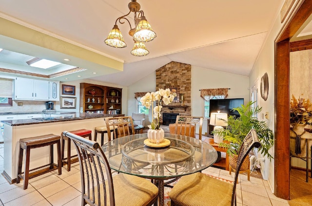 1027 Peggys Cv, Reynoldsburg, OH 43068 - dining space with light tile patterned flooring, a stone fireplace, a chandelier, lofted ceiling, and a skylight