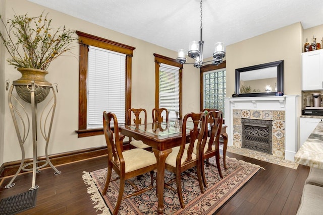 540 Linwood Ave, Columbus, OH 43205 - dining room featuring a chandelier, dark wood-style floors, a tiled fireplace, baseboards, and a textured ceiling