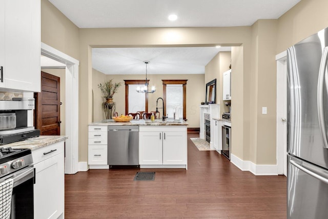 540 Linwood Ave, Columbus, OH 43205 - kitchen with stainless steel appliances, a sink, white cabinets, a peninsula, and dark wood-type flooring