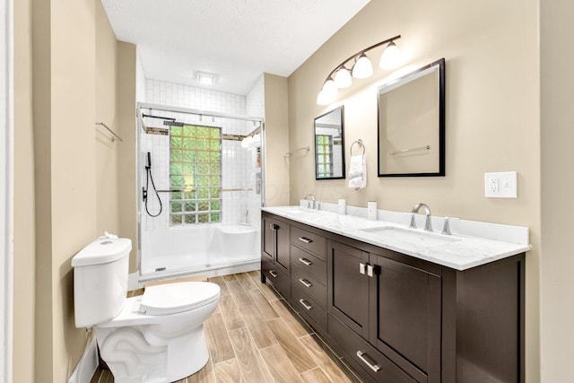 540 Linwood Ave, Columbus, OH 43205 - full bathroom featuring toilet, double vanity, a stall shower, a textured ceiling, and wood tiled floors