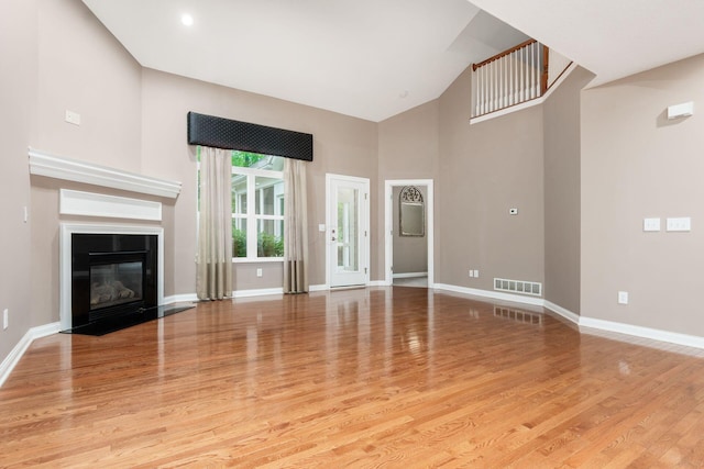 6618 Wild Rose Ln, Westerville, OH 43082 - unfurnished living room with high vaulted ceiling, light wood-style flooring, baseboards, and a premium fireplace