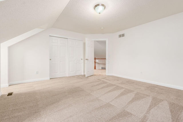 6618 Wild Rose Ln, Westerville, OH 43082 - unfurnished bedroom with a textured ceiling, light colored carpet, lofted ceiling, a closet, and baseboards