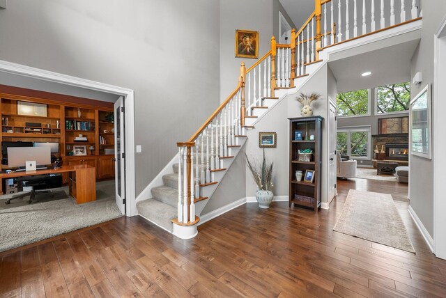 6034 Heritage View Ct, Hilliard, OH 43026 - stairs with a high ceiling, hardwood / wood-style floors, baseboards, and a stone fireplace
