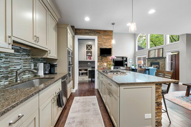 6034 Heritage View Ct, Hilliard, OH 43026 - kitchen with a fireplace, a sink, stainless steel appliances, a center island, and tasteful backsplash