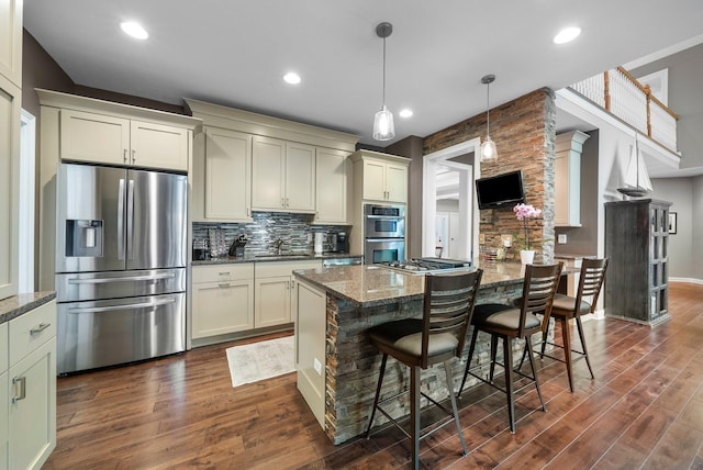 6034 Heritage View Ct, Hilliard, OH 43026 - kitchen featuring appliances with stainless steel finishes, decorative backsplash, dark wood-style floors, dark stone counters, and a breakfast bar