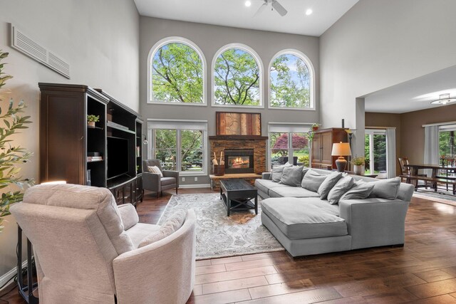 6034 Heritage View Ct, Hilliard, OH 43026 - living room featuring a towering ceiling, ceiling fan, dark wood finished floors, and a stone fireplace