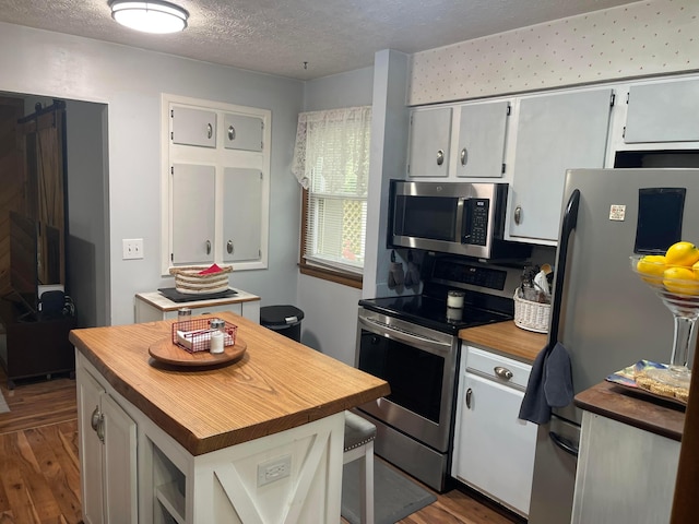 314 Broken Arrow Rd, Columbus, OH 43230 - kitchen with butcher block counters, appliances with stainless steel finishes, dark wood-style flooring, a textured ceiling, and white cabinetry