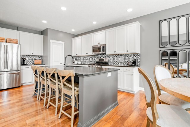 2505 Isabella Blue Dr, Powell, OH 43065 - kitchen featuring stainless steel appliances, a sink, an island with sink, light wood-style flooring, and backsplash
