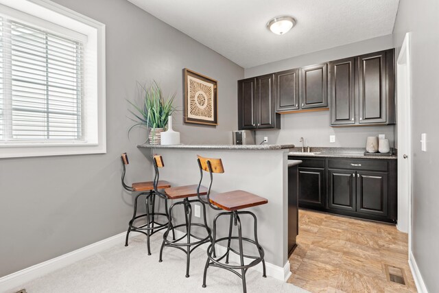 2505 Isabella Blue Dr, Powell, OH 43065 - kitchen with a breakfast bar area, a sink, baseboards, light countertops, and a peninsula