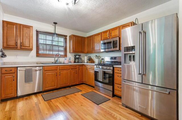 1315 Shelby Cir, Reynoldsburg, OH 43068 - kitchen featuring stainless steel appliances, light countertops, brown cabinets, light wood-style floors, and a textured ceiling