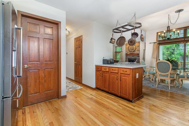 1315 Shelby Cir, Reynoldsburg, OH 43068 - kitchen featuring stainless steel fridge, light wood finished floors, light countertops, brown cabinets, and a fireplace