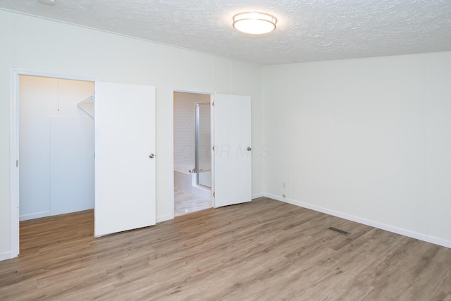 160 Cliff St, Buckeye Lake, OH 43008 - unfurnished bedroom with a textured ceiling, wood finished floors, a walk in closet, a closet, and ensuite bath