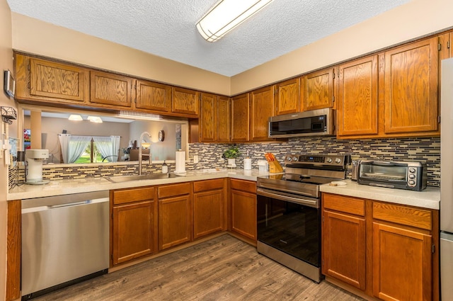 7179 Inverness Ct, Dublin, OH 43016 - kitchen featuring appliances with stainless steel finishes, light countertops, a sink, dark wood finished floors, and tasteful backsplash