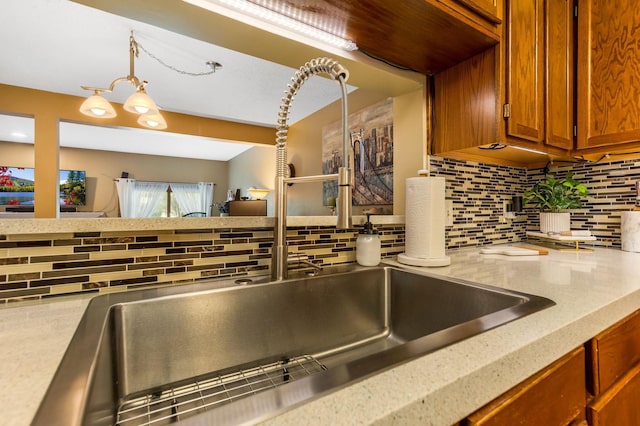 7179 Inverness Ct, Dublin, OH 43016 - kitchen view of brown cabinetry, tasteful backsplash, hanging light fixtures, a sink, and light stone counters