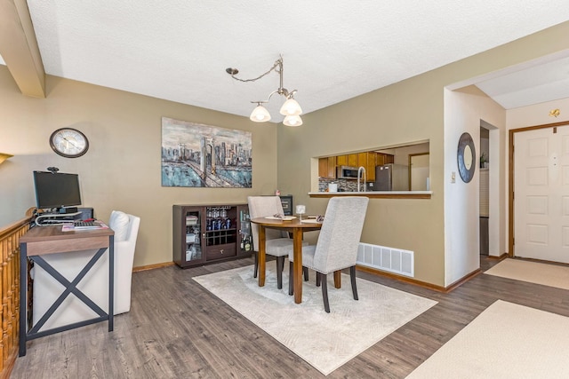 7179 Inverness Ct, Dublin, OH 43016 - dining space with wood finished floors, a chandelier, baseboards, and a textured ceiling
