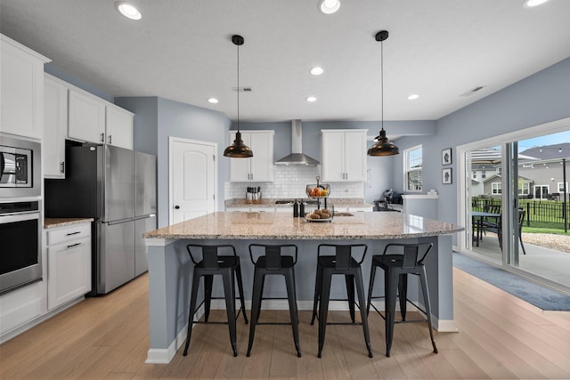3834 Brody Dr, Grove City, OH 43123 - kitchen featuring wall chimney exhaust hood, appliances with stainless steel finishes, tasteful backsplash, light wood-style floors, and white cabinetry