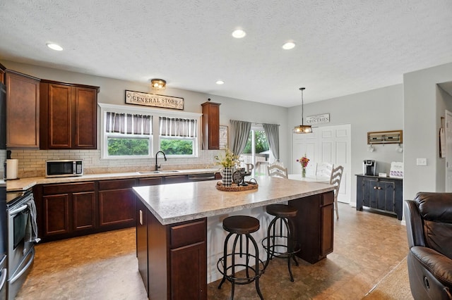 459 Wingate Pl, Mount Sterling, OH 43143 - kitchen with appliances with stainless steel finishes, a sink, a kitchen island, backsplash, and a breakfast bar