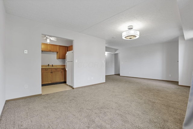 3939 Karl Rd Unit 206, Columbus, OH 43224 - unfurnished living room featuring light carpet, baseboards, a ceiling fan, a textured ceiling, and a sink