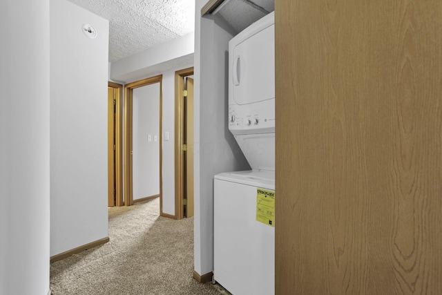 3939 Karl Rd Unit 206, Columbus, OH 43224 - washroom with stacked washer and clothes dryer, carpet floors, baseboards, and a textured ceiling