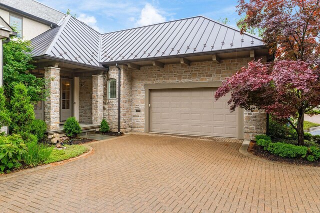 14 Lyonsgate Rd, Bexley, OH 43209 - view of front of house with a standing seam roof, decorative driveway, metal roof, and stone siding