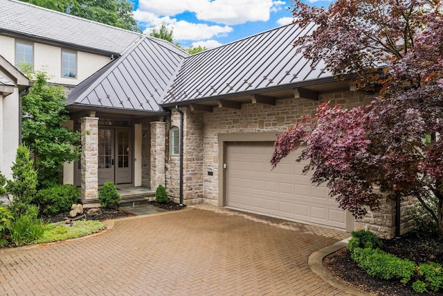 14 Lyonsgate Rd, Bexley, OH 43209 - view of front of house featuring a standing seam roof, french doors, metal roof, stone siding, and an attached garage