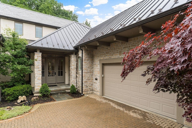 14 Lyonsgate Rd, Bexley, OH 43209 - property entrance featuring a standing seam roof, stone siding, metal roof, decorative driveway, and a garage