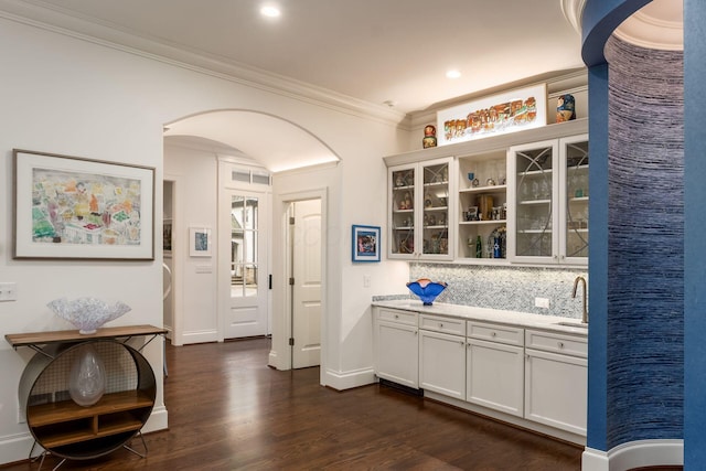14 Lyonsgate Rd, Bexley, OH 43209 - bar area featuring dark wood-type flooring, ornamental molding, arched walkways, a sink, and tasteful backsplash